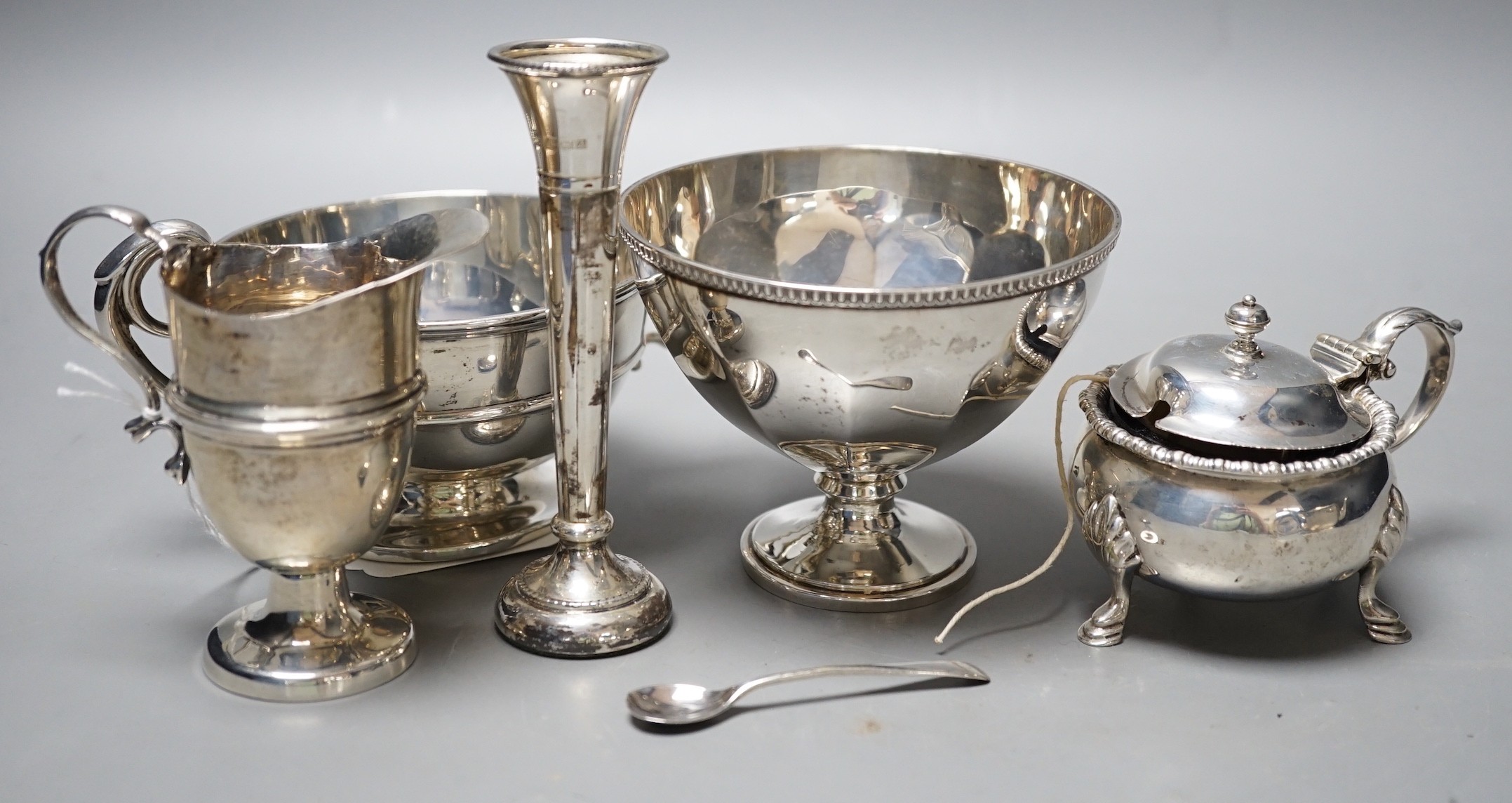 A late Victorian silver helmet shaped cream jug, a silver sugar bowl, a silver mustard pot, a silver mounted posy vase and a silver two handled bowl.